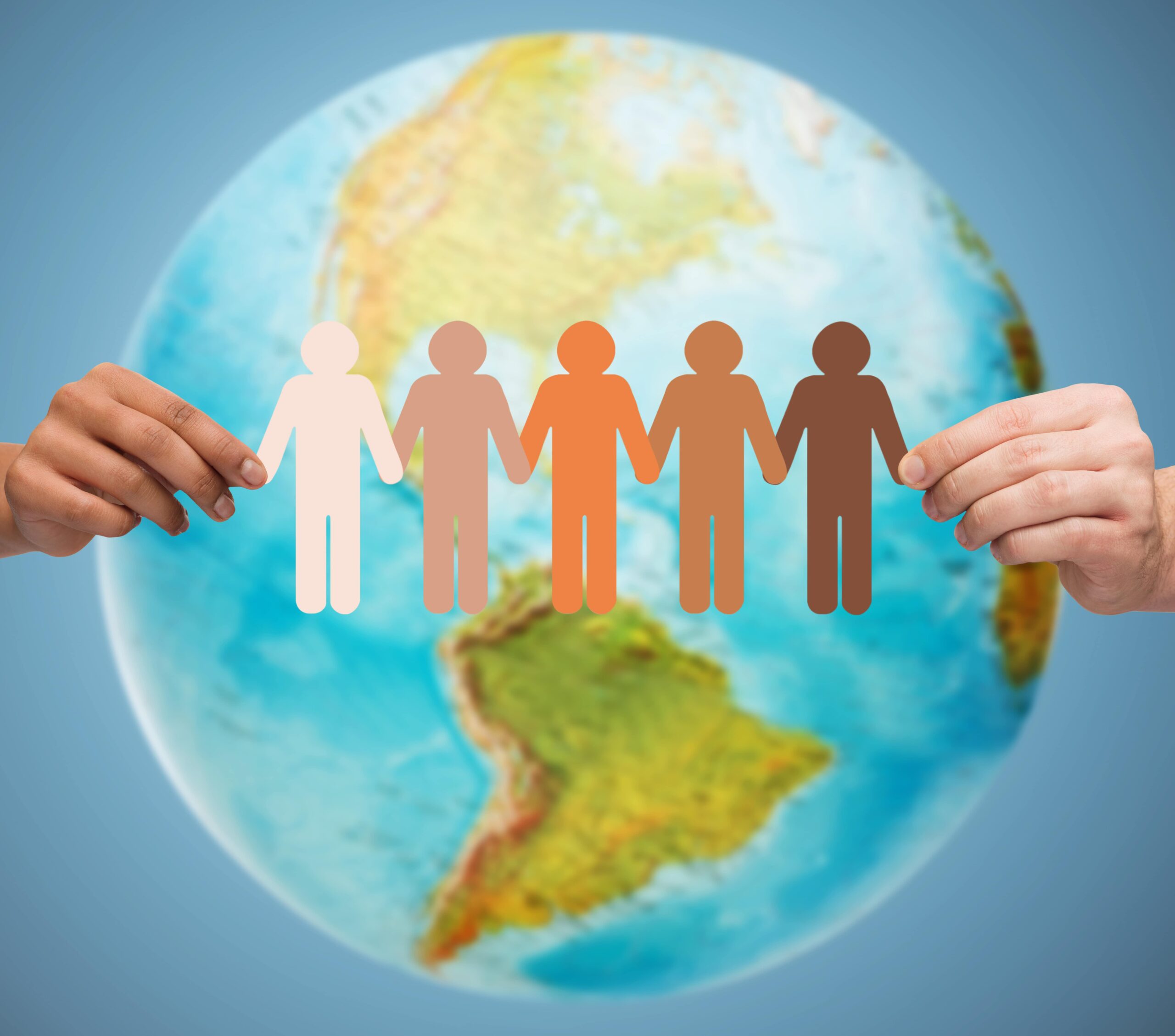 Hands holding a multicultural paper chain of people in front of a globe, symbolising global unity and diversity