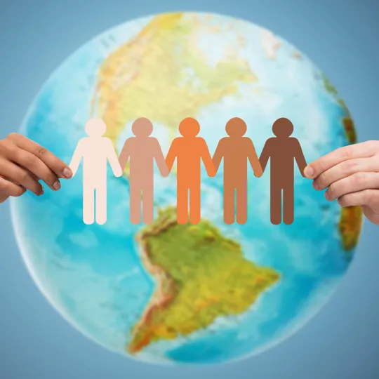 Hands holding a multicultural paper chain of people in front of a globe, symbolising global unity and diversity