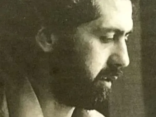 A close-up sepia photograph of John Coffey, who joined Wolsey Hall Oxford as Principal in 1987. John is looking down to the right. He has bushy black hair and a black beard and mustache.