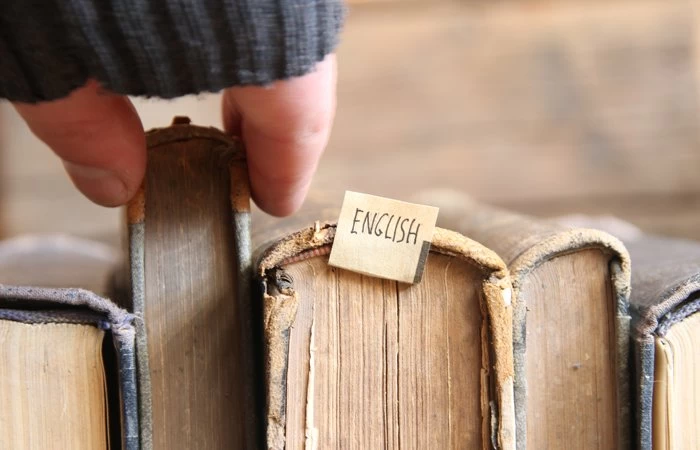A collection of old books, one of which has a note with the word 'English' on. 