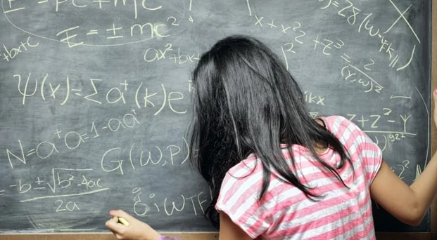 A maths student writing her equations on a blackboard. 