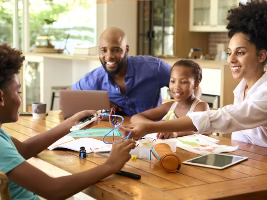 Parents and children collaborating on a creative project at home with learning materials