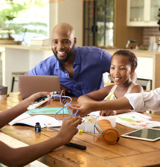 Parents and children collaborating on a creative project at home with learning materials
