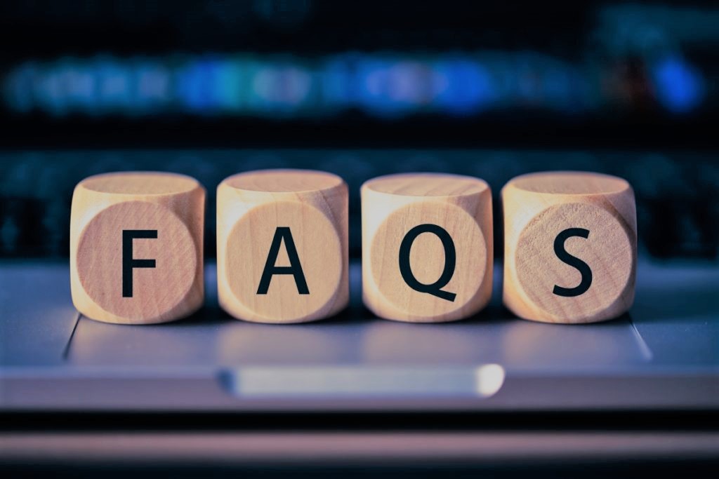 Wooden blocks on a laptop keyboard spelling the word FAQs.
