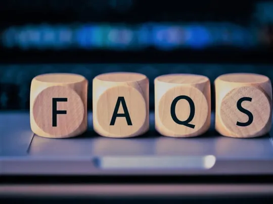 Wooden blocks on a laptop keyboard spelling the word FAQs.