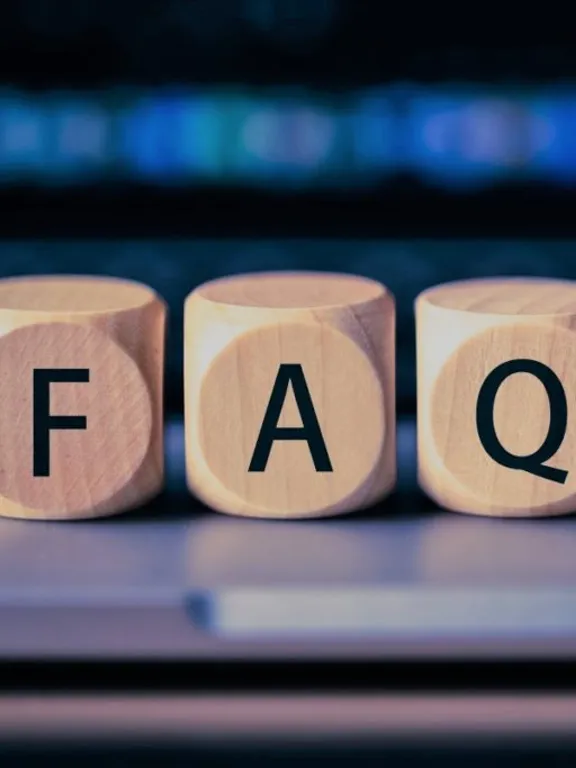 Wooden blocks on a laptop keyboard spelling the word FAQs.