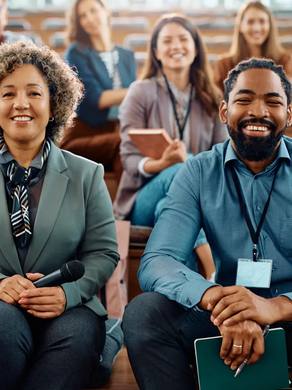 A group of diverse teachers sat in a group smiling at the camera, representing the teachers at Pamoja
