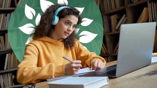 A student with curly hair wearing headphones, writing in a notebook while looking at a laptop, with a blurred bookshelf background and a green leafy design.