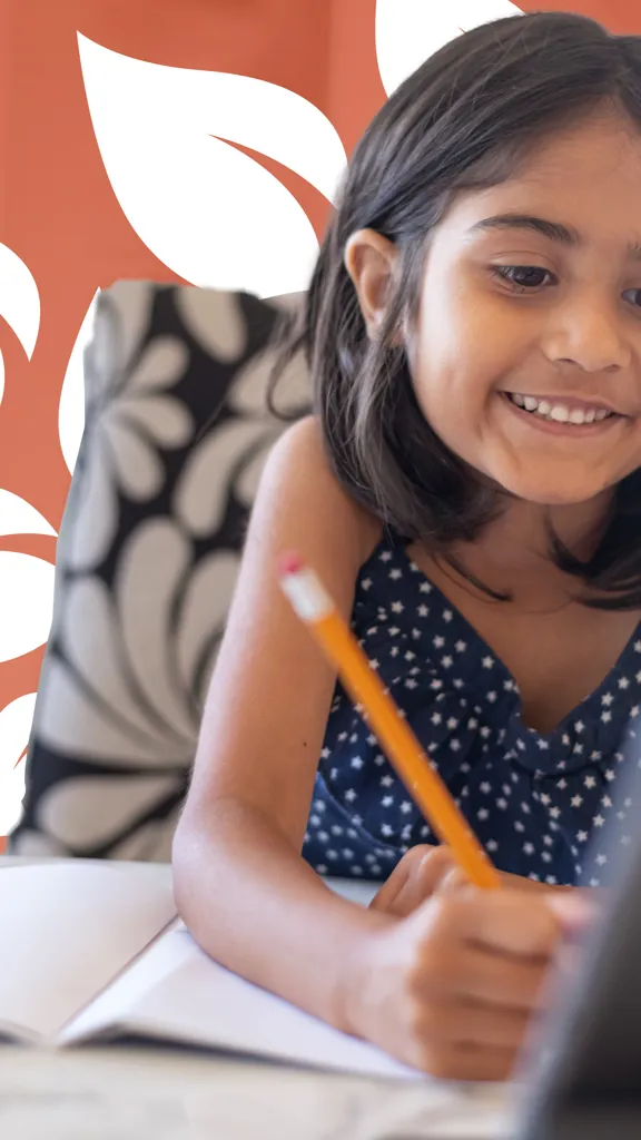 A young student smiling and writing in a notebook while looking at a tablet, with a leafy design in the background.