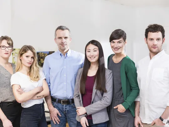 Diverse team of six professionals posing together in a well-lit office space.