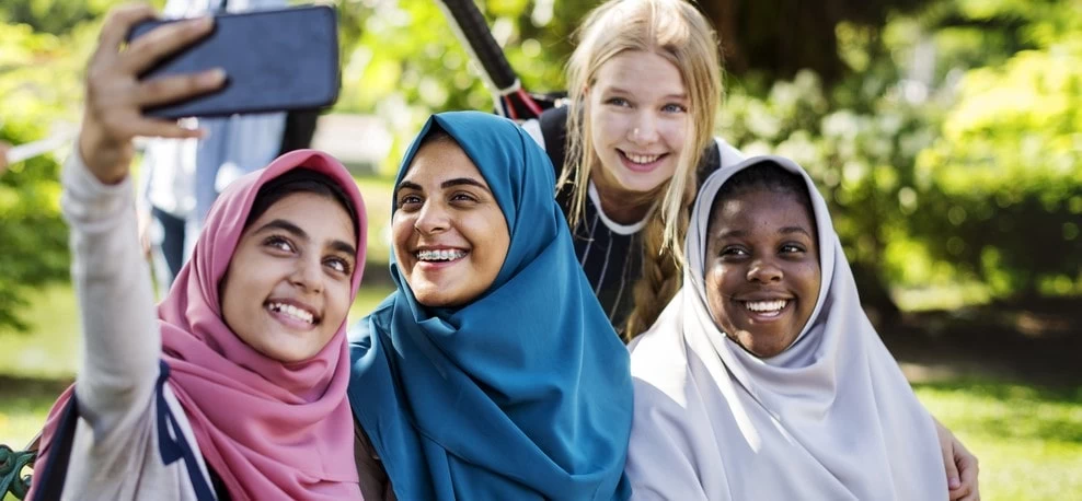 Teenagers using a phone to take a group photo.