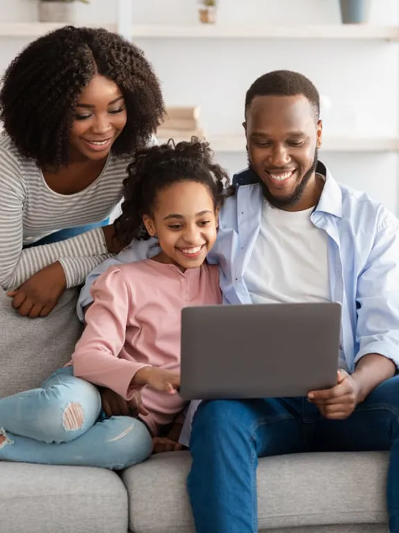 Family on couch watching a Wolsey Hall Oxford online open event on a laptop