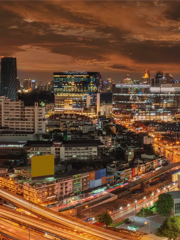 Illuminated Bangkok cityscape at night with glowing highways and high-rise buildings.