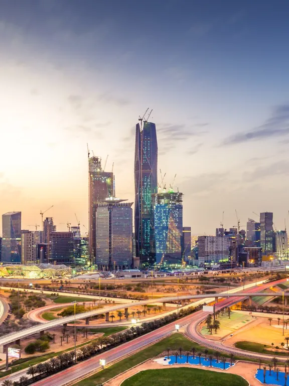 Expansive evening view of the Riyadh, Saudi Arabia skyline with illuminated skyscrapers and city lights.