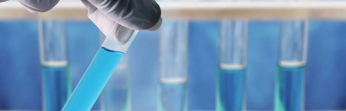 Close up of scientist inspecting a test tube with fluid inside. 