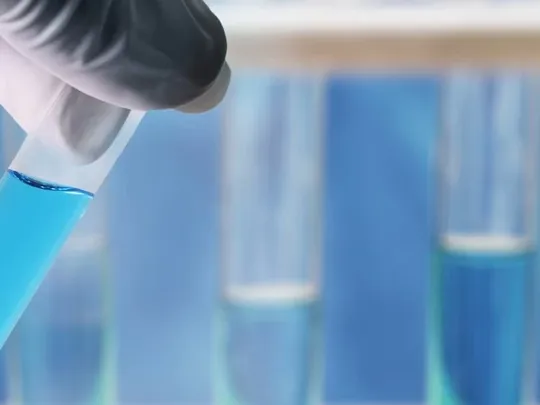 Close up of scientist inspecting a test tube with fluid inside.