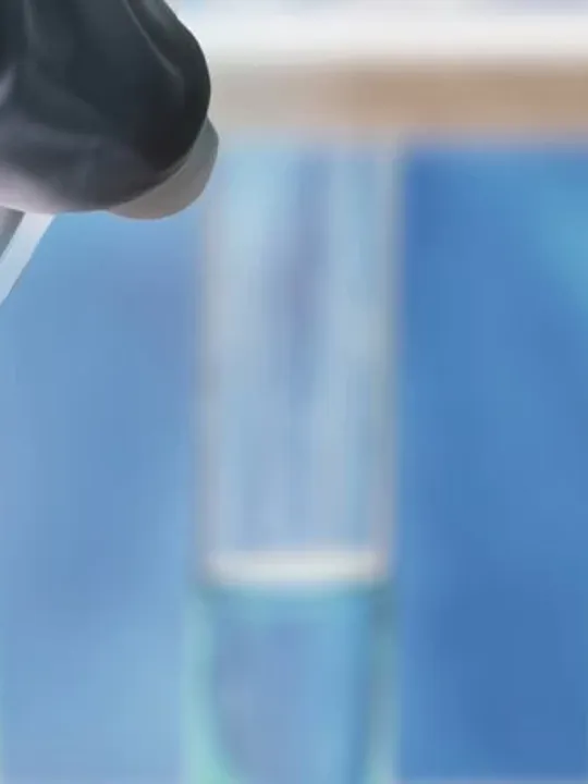Close up of scientist inspecting a test tube with fluid inside.