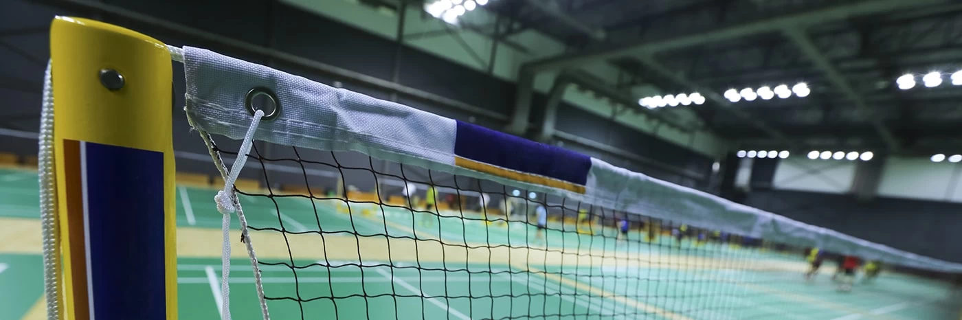 Close up of a badminton net and post on a court in an indoor sports hall.