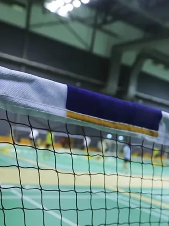 Close up of a badminton net and post on a court in an indoor sports hall.