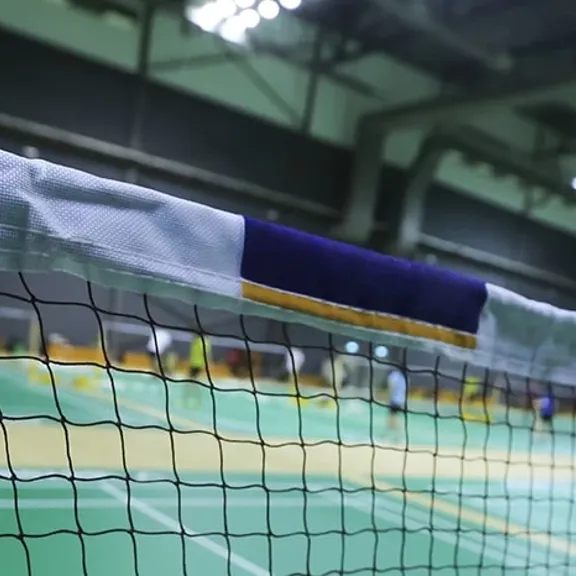 Close up of a badminton net and post on a court in an indoor sports hall.