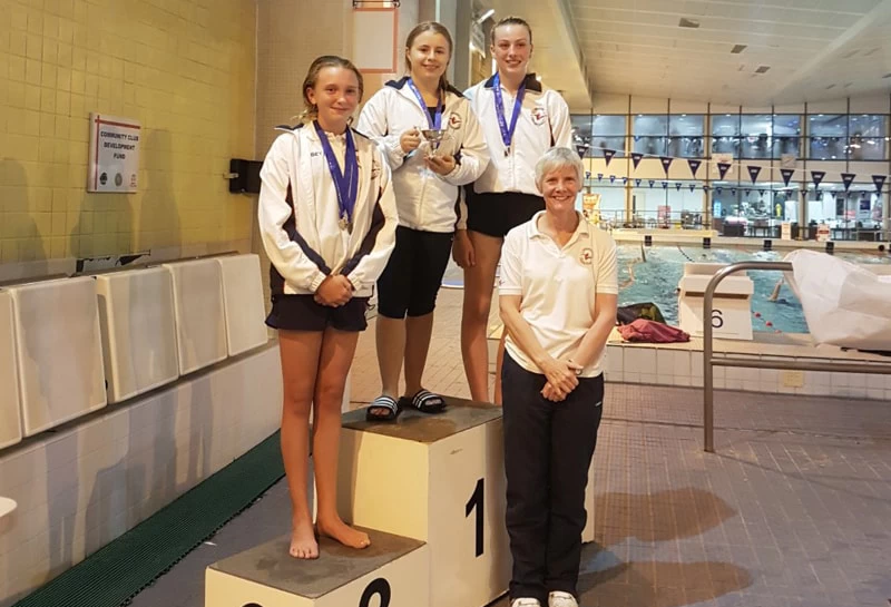 WHO student and diver, Olivia, on a medal podium.