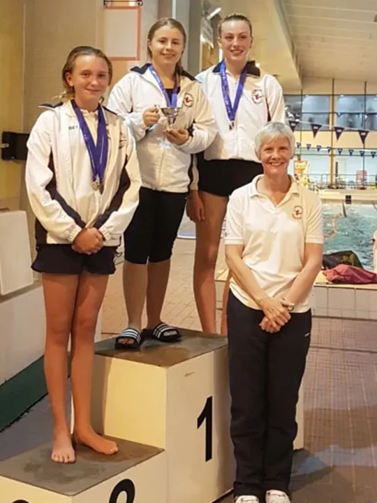 WHO student and diver, Olivia, on a medal podium.