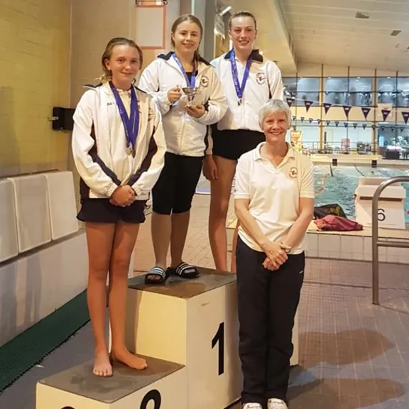 WHO student and diver, Olivia, on a medal podium.