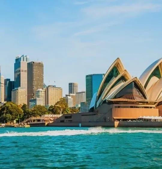 A landscape view of the Sydney Opera House, and the surrounding skyline.
