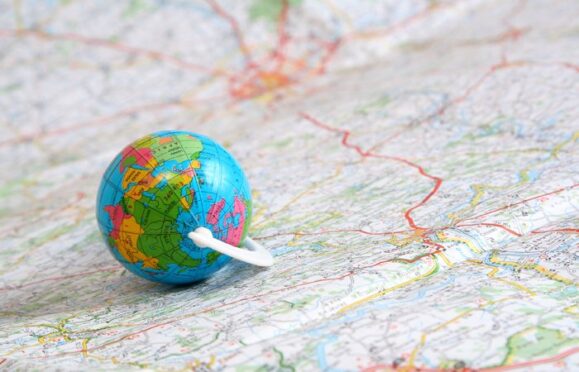 A small sized globe, on top of a large map. 