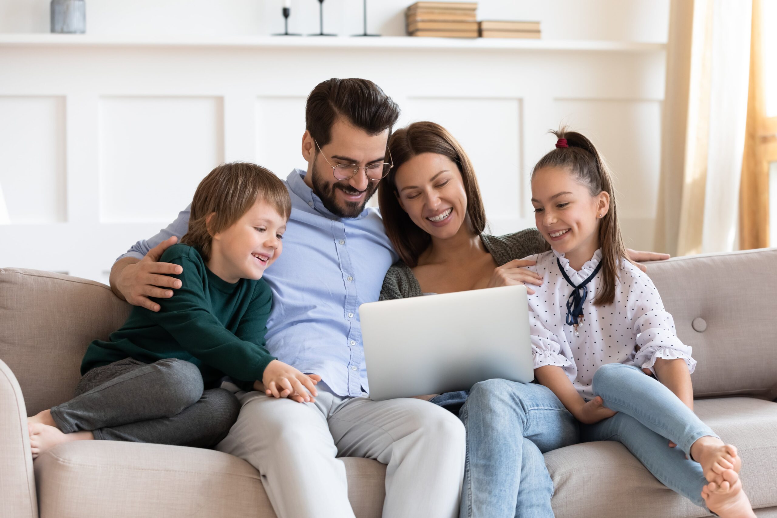 Smiling family engaging with a laptop, representing a positive approach to homeschooling.