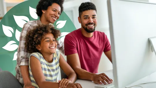 Smiling parents and child at home using a desktop computer for learning