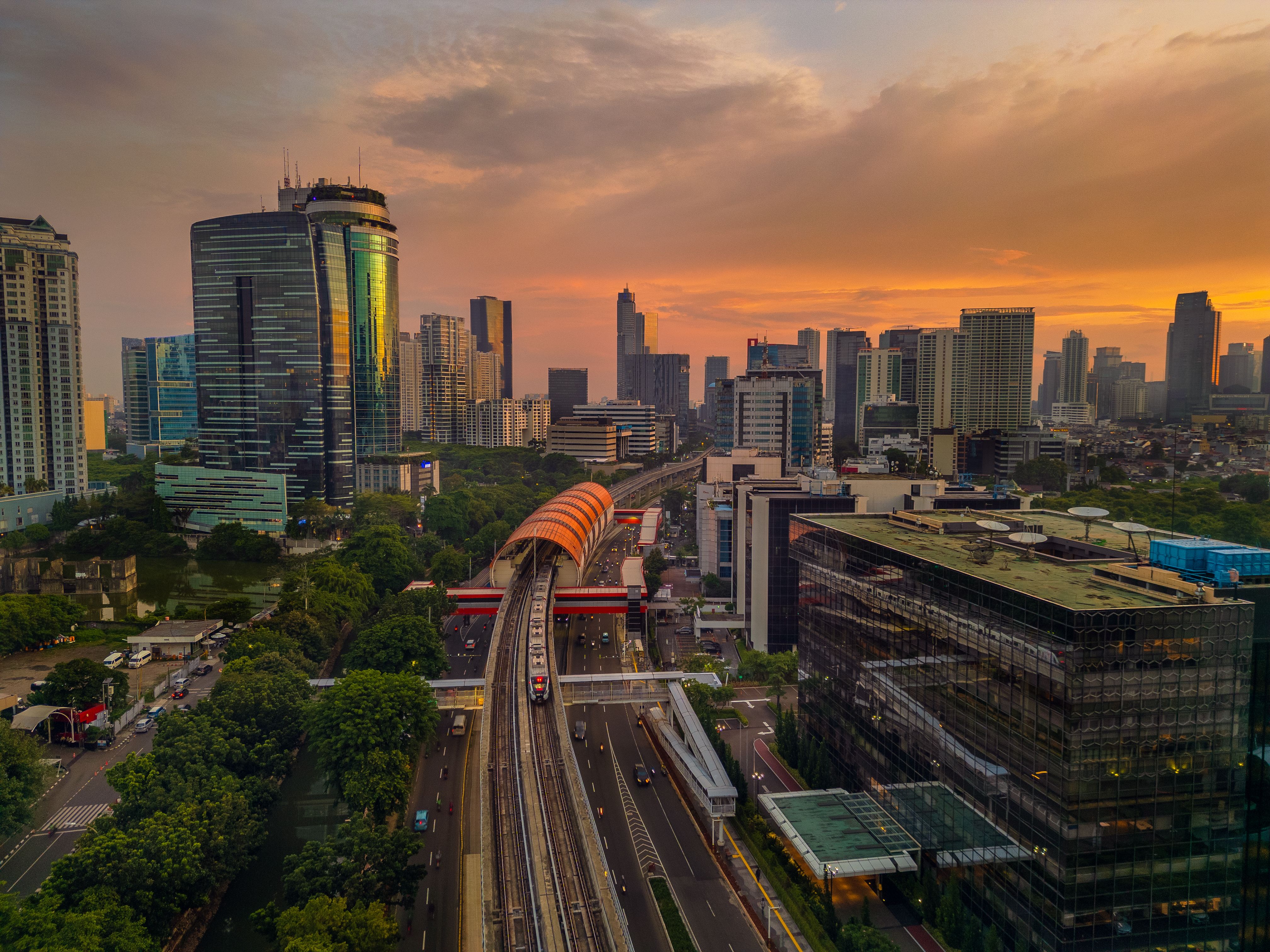 Panoramic sunset view of the Jakarta cityscape with modern skyscrapers and an MRT train, illustrating the vibrant urban setting for families exploring homeschooling options in Jakarta.