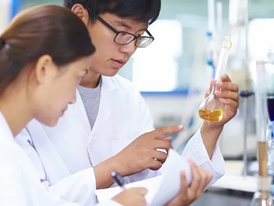Chemistry students examining liquid in a scientific experiment.