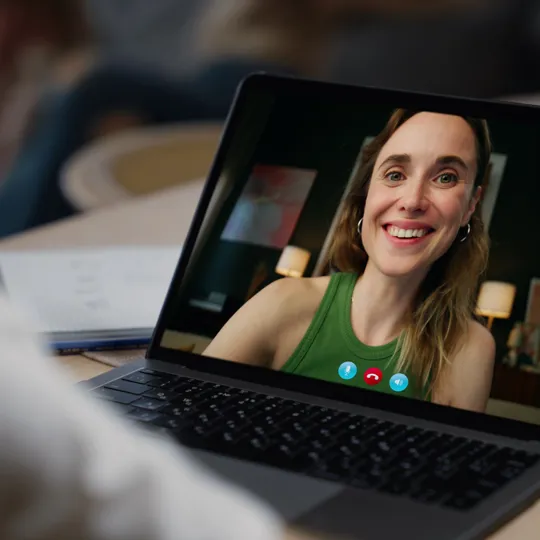 Close-up of a laptop screen showing a smiling tutor on a video call with a student.