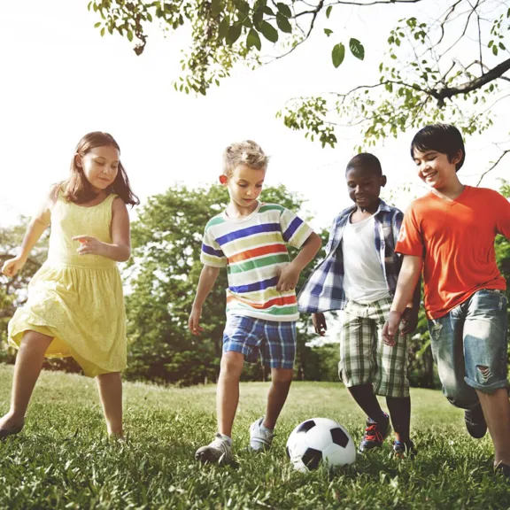 Group of young children running and kicking a football.