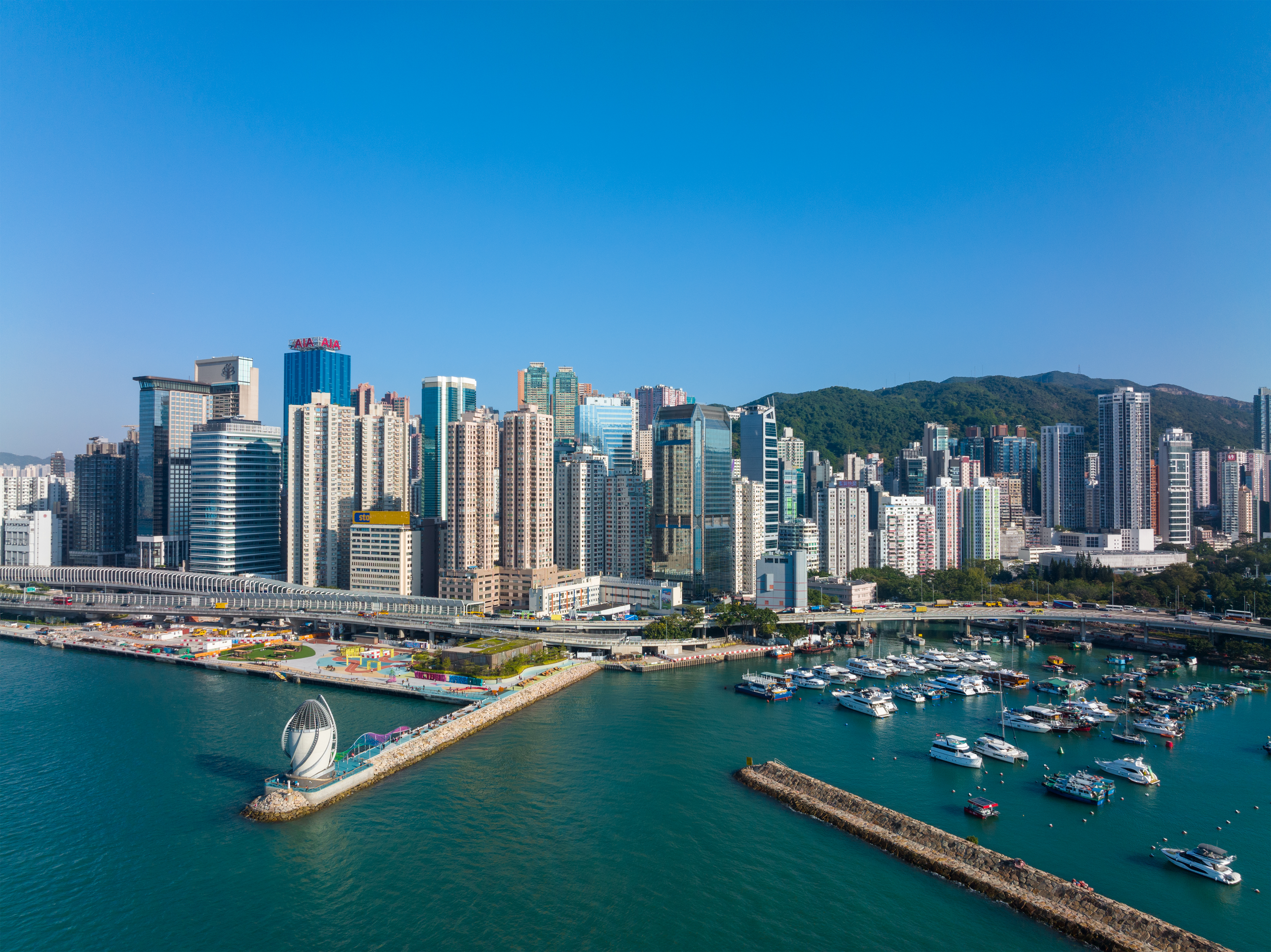 Modern high-rise skyline of Hong Kong overlooking Victoria Harbour and docked boats.