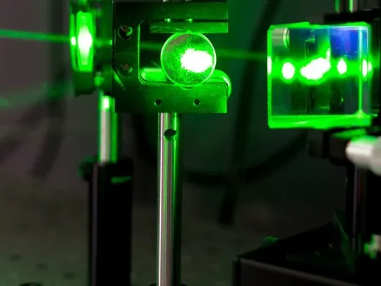 Lasers being shone through a glass prism to test reflection and refraction for a science experiment