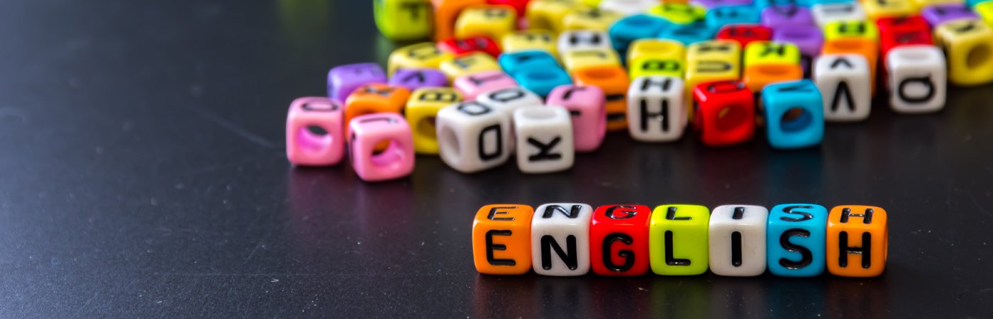 Colourful letter beads scattered on a black surface, with the word “ENGLISH” spelled out in the foreground