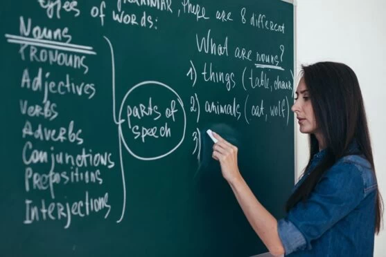 An English teacher writing on a blackboard. 