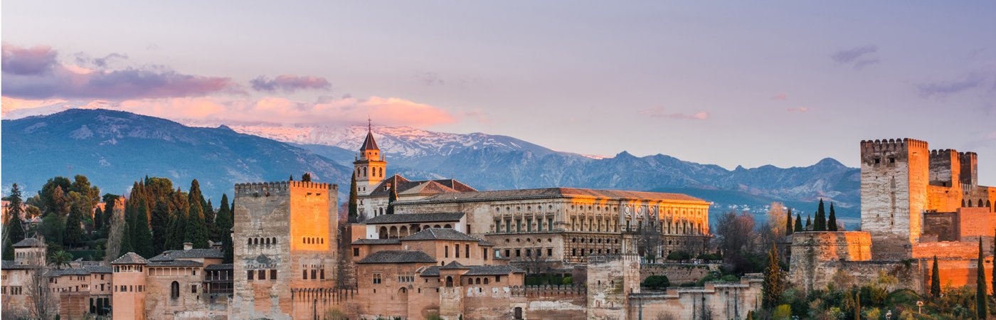 A landscape view of a Spanish castle at sunset. 