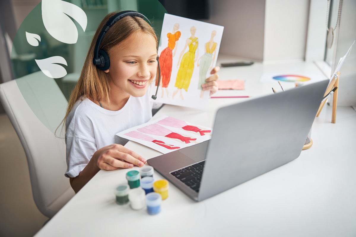 Smiling girl with headset sharing fashion sketches during online art class