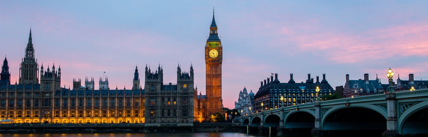 London’s Big Ben and Houses of Parliament glowing at sunset, viewed across the River Thames.