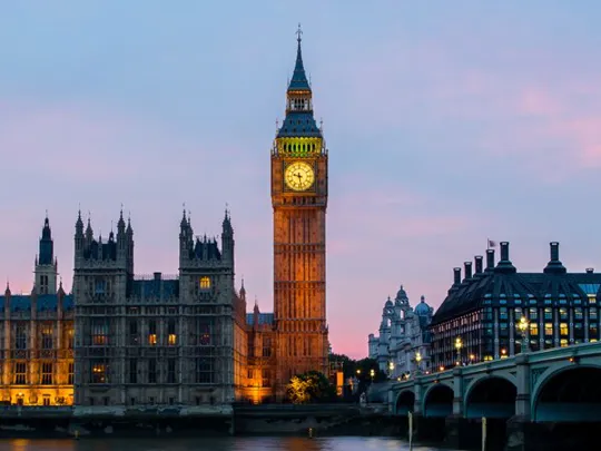 London’s Big Ben and Houses of Parliament glowing at sunset, viewed across the River Thames.