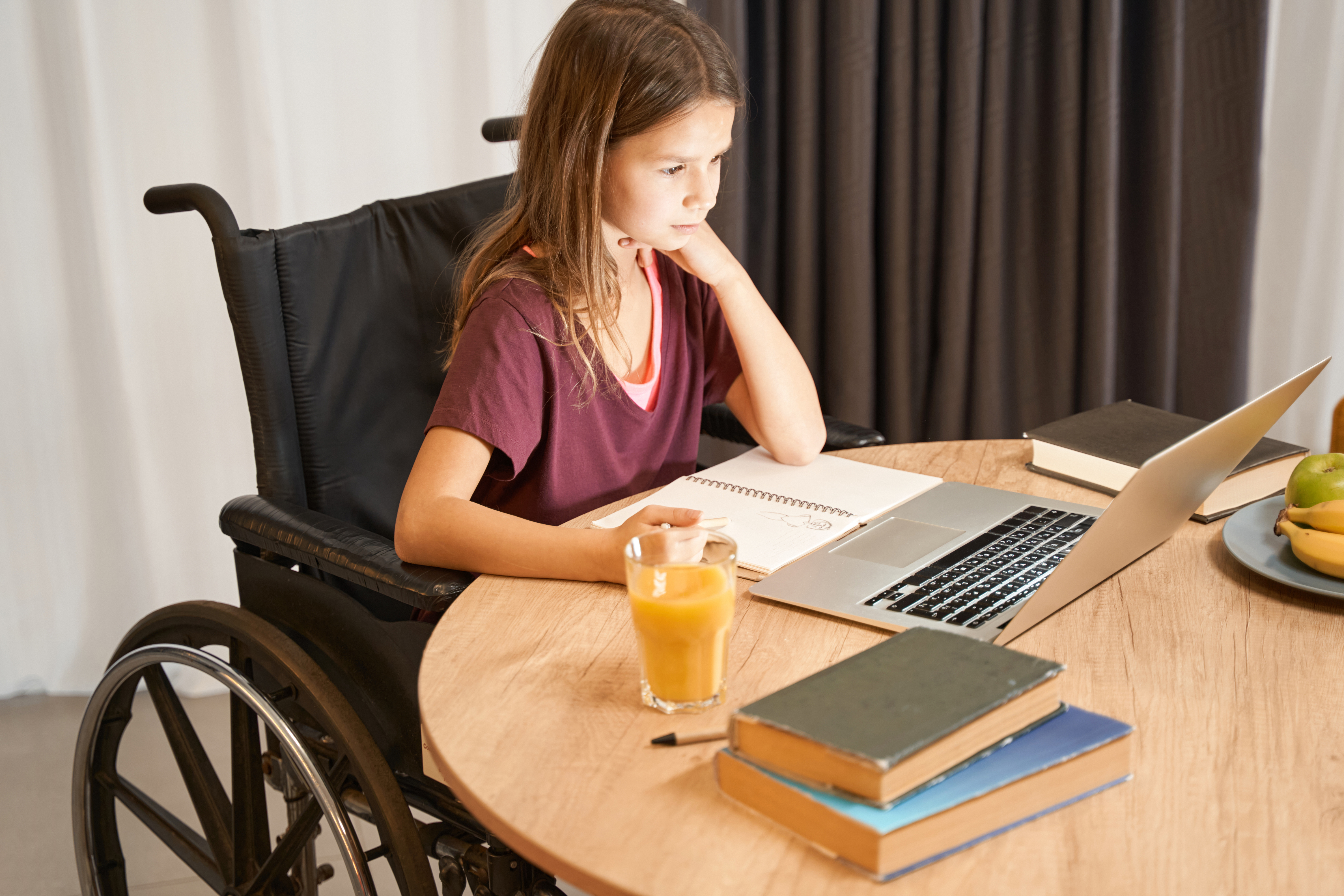 oung girl in a wheelchair diligently studying on a laptop, representing homeschooling for children with ill health and disabilities at our on-demand open event.
