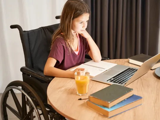 oung girl in a wheelchair diligently studying on a laptop, representing homeschooling for children with ill health and disabilities at our on-demand open event.