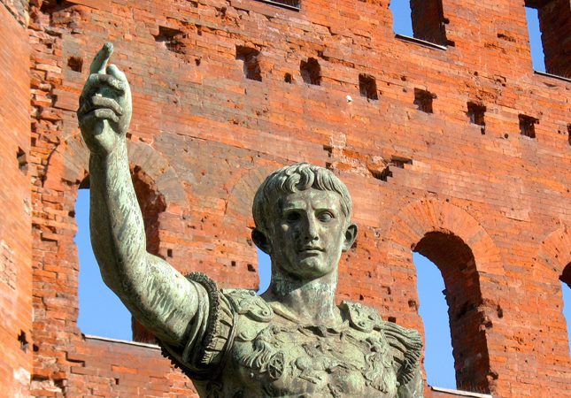 An old roman statue outside made from oxidised copper. 