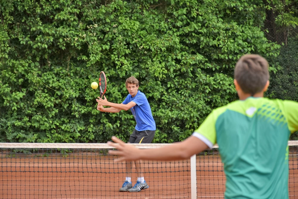 Two boys playing tennis together. 
