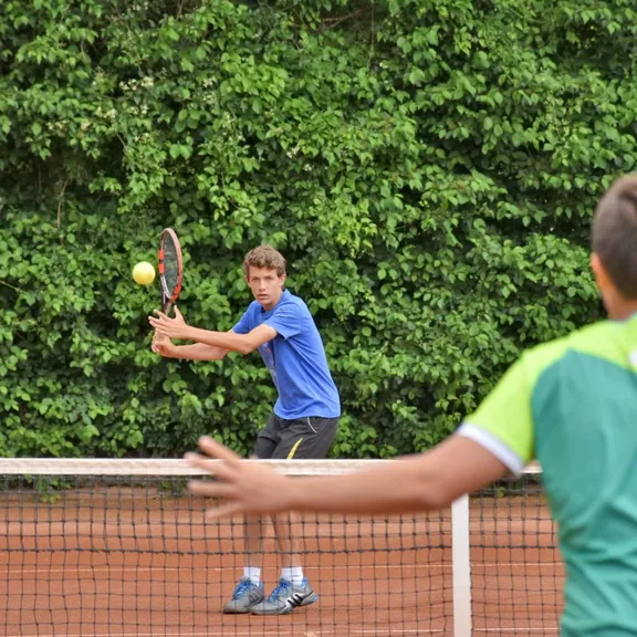 Two boys playing tennis together.