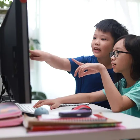 Brother and sister learning together on a computer.