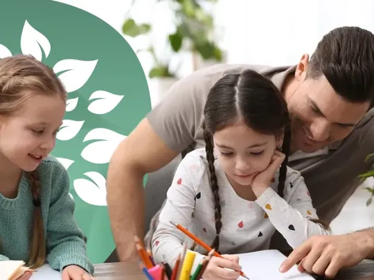A dad homeschooling his two young daughters at a desk.